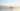 Group of people enjoying a relaxed walk in the ocean at sunset, symbolising stress relief, calmness and wellbeing during the busy holiday season.