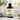 A bottle of About Health Gentle Care Wash soap-free shampoo, set on a marble countertop with a green towel and potted plants in a bright bathroom setting.