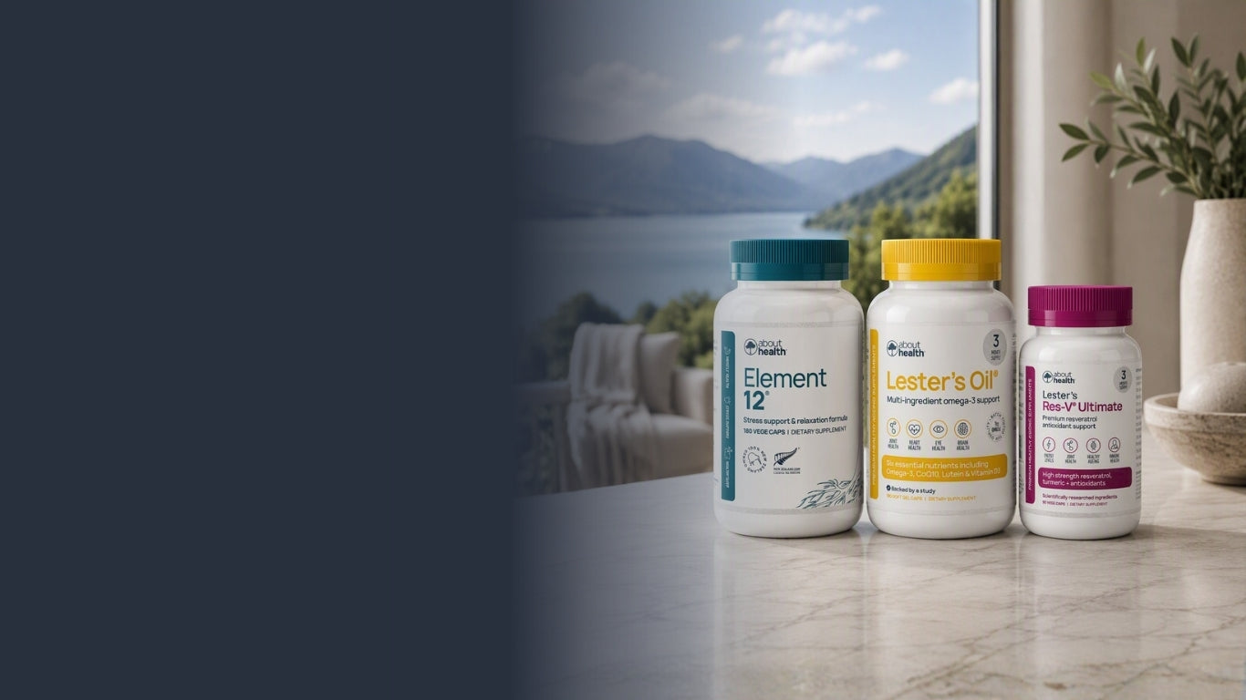 Three white supplement bottles with teal, yellow, and magenta caps sit on a marble countertop in front of a window showing a scenic lake and mountains. The bottles are branded with About Health.