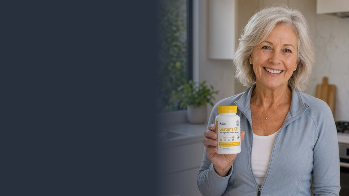 A smiling older woman with short gray hair stands in a bright kitchen, holding up bottle of Lester's Oil with a yellow cap. The left side of the image has a dark blue vertical overlay.