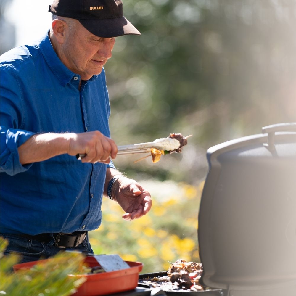Man grilling outdoors using tongs on a summers day.