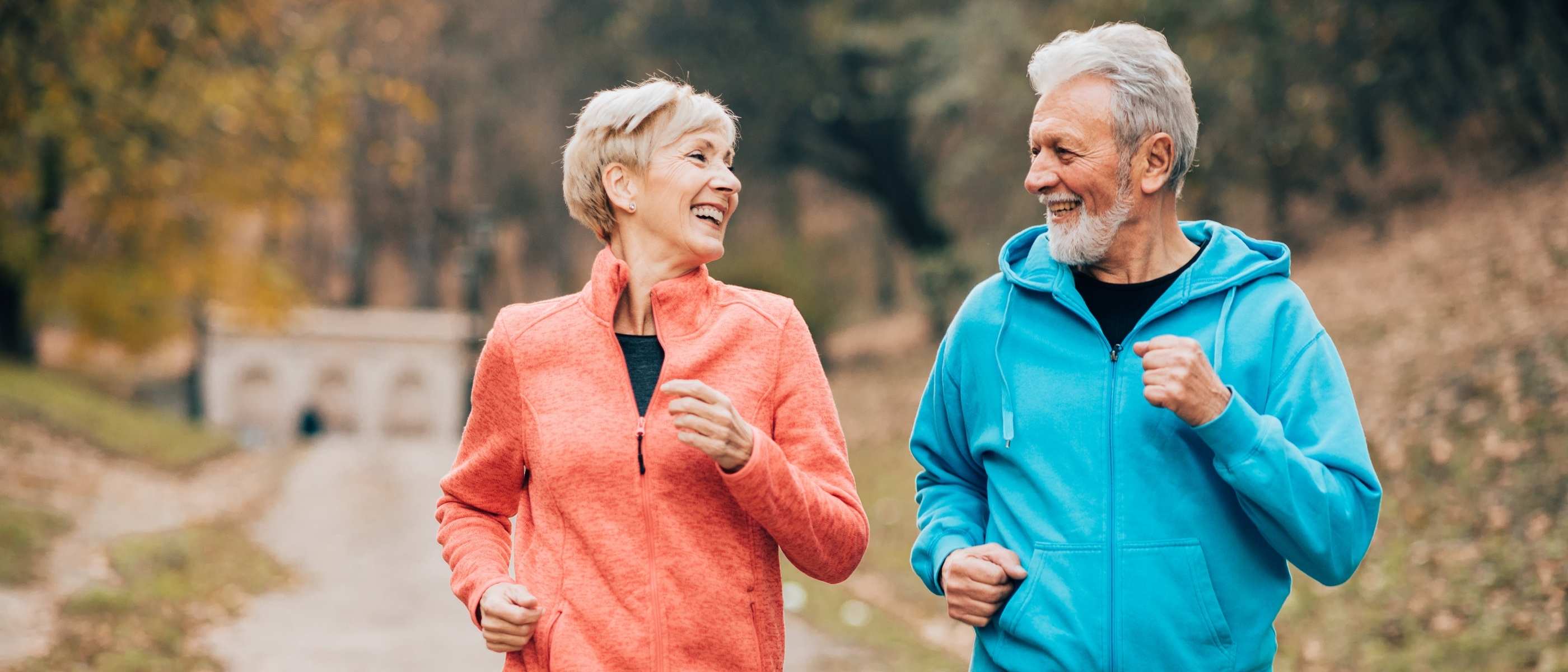 Two people jogging outdoors on a path with trees in the background
