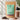 A 1 kg stand-up pouch of Kiwi Nutrition Pea Protein Isolate in Rich Chocolate flavor, displayed alongside a shaker bottle filled with chocolate powder, loose chocolate pieces, and a spoon of powder, with product feature icons on the left and a plant in the background.