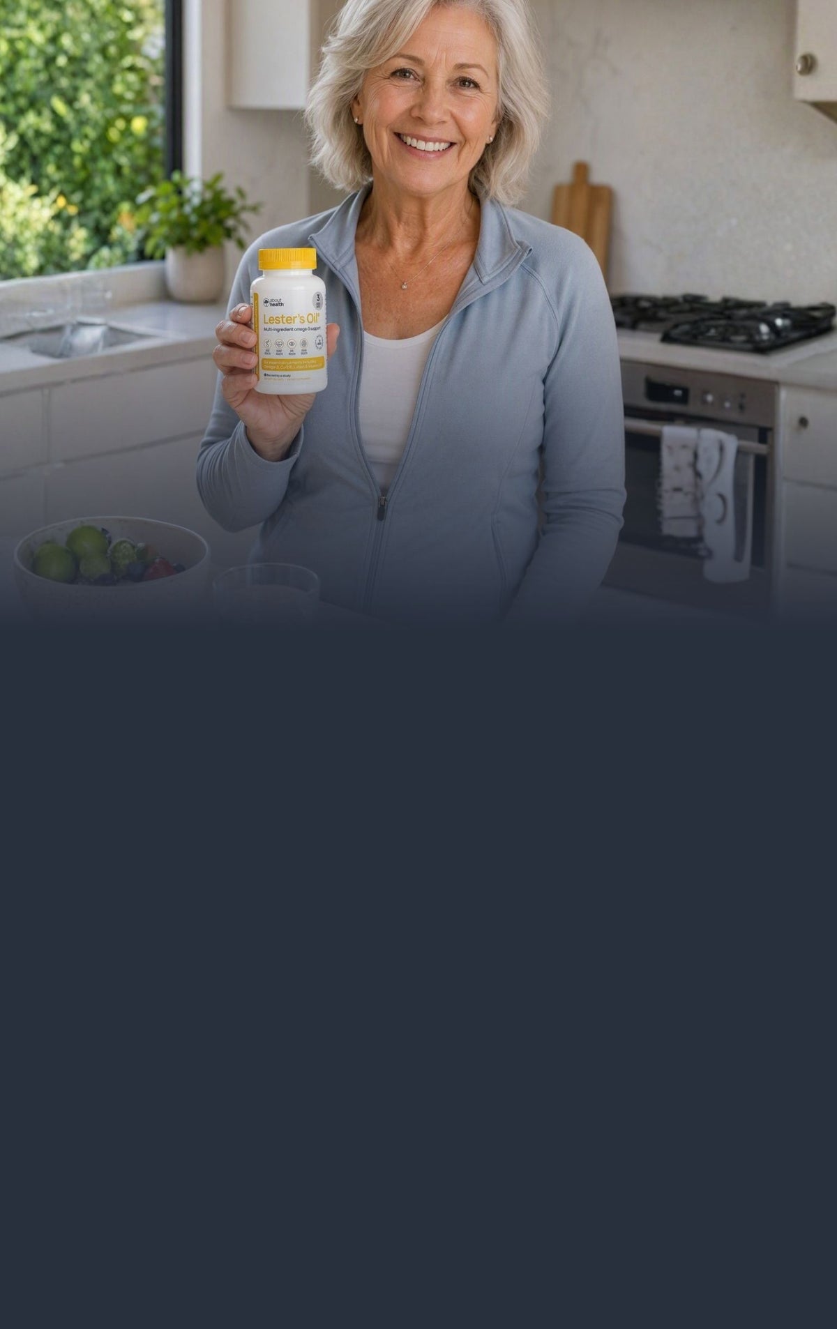 A smiling older woman in a light blue zip-up jacket stands in a bright kitchen, holding up a bottle of Lester's Oil with a yellow cap. The image has a dark blue gradient overlay at the bottom.