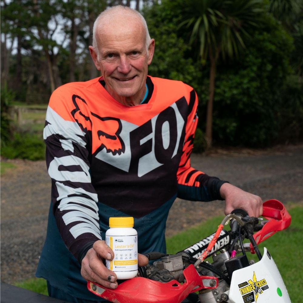 Phil taking a picture after doing motorcross, holding a bottle of Lester's Oil. 