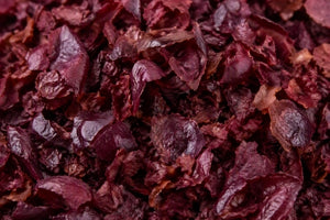 A close-up view of dried, shredded dark red and red grape skin filling the entire frame.