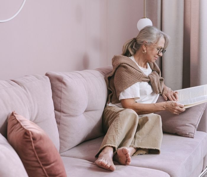 Woman relaxing on a couch and reading in cosy living room.