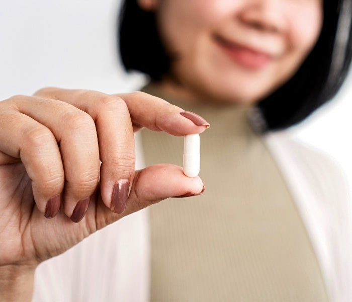 Close-up of a hand holding a capsule, representing Element 12 Magnesium.