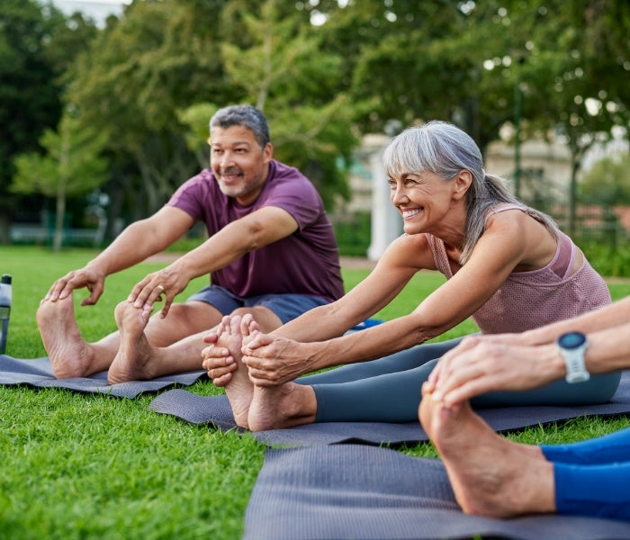 Group of people stretching outdoors on a grassy area.