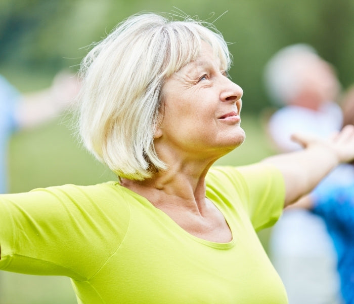 Woman in a green shirt stretching outdoors.
