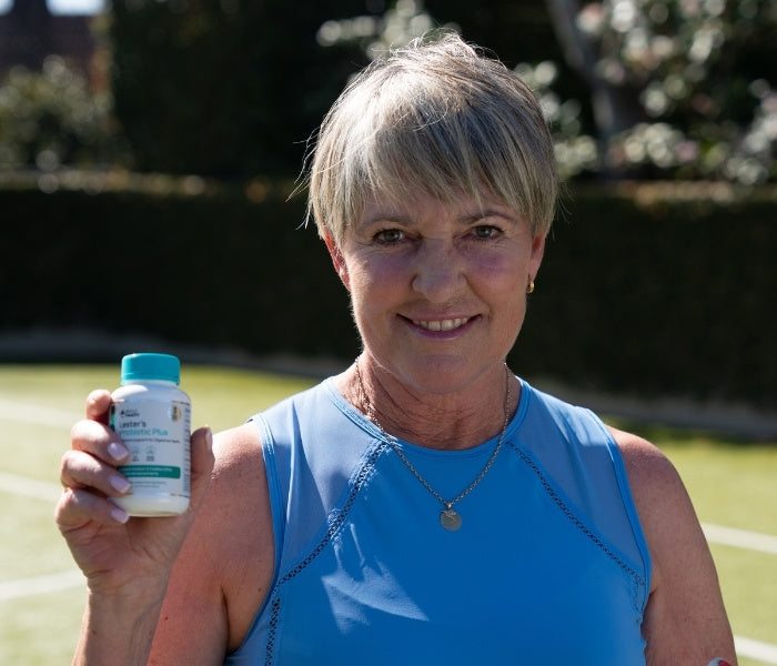 Woman holding a bottle of Lester's Probiotic Plus outside.