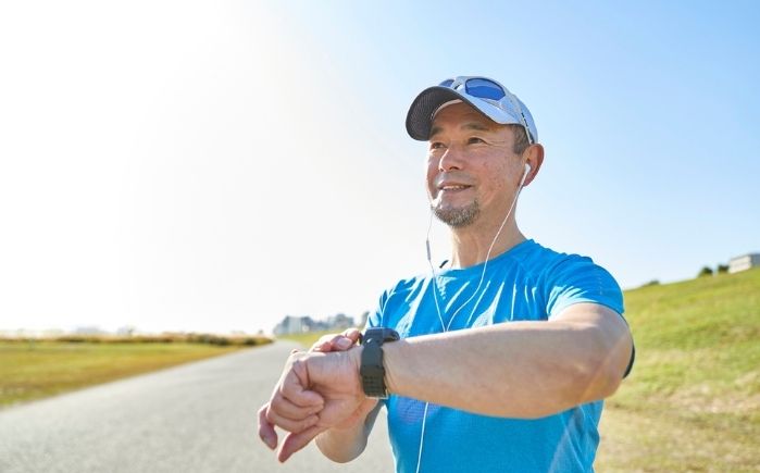 Man in blue shirt and cap with earphones outdoors on a sunny day.